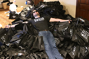 A hacker resting on a large pile of swag bags
